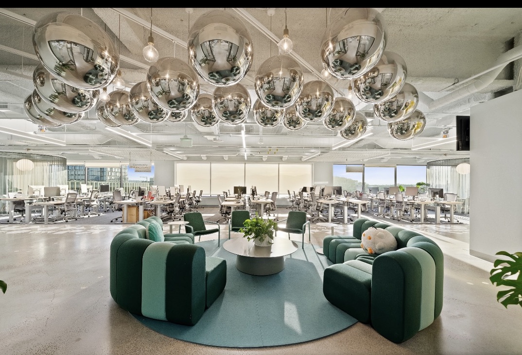 A lounge with green chairs and chrome pendants in a Market Street office designed by McArthur Design Studio